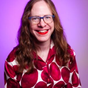 Kat Rohn, long red hair, glasses and red/white shirt